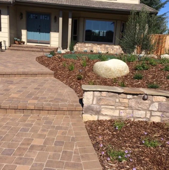 Paver walkway with stone planter in a finished front yard